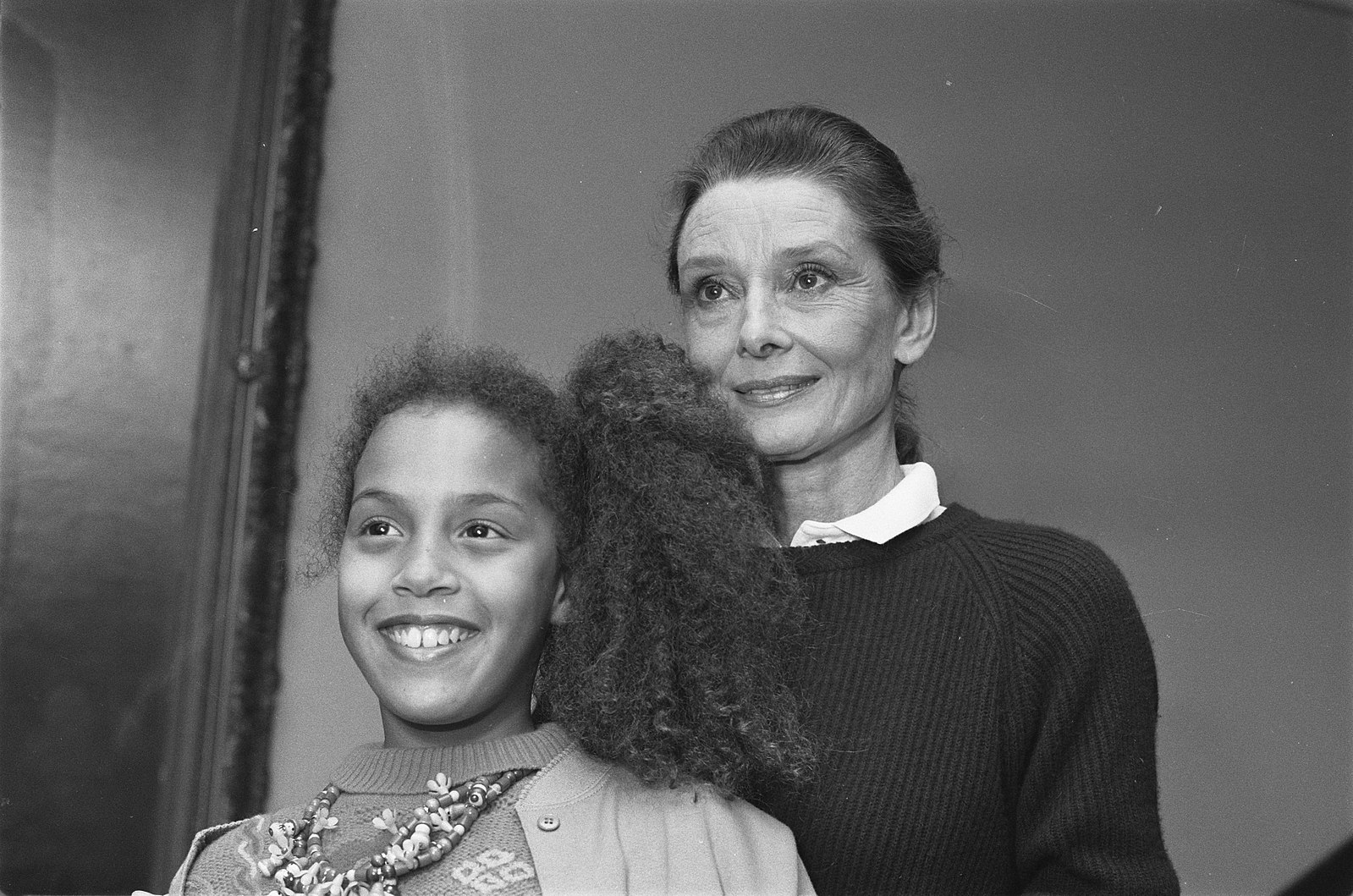 woman in collared shirt stands next to young girl
