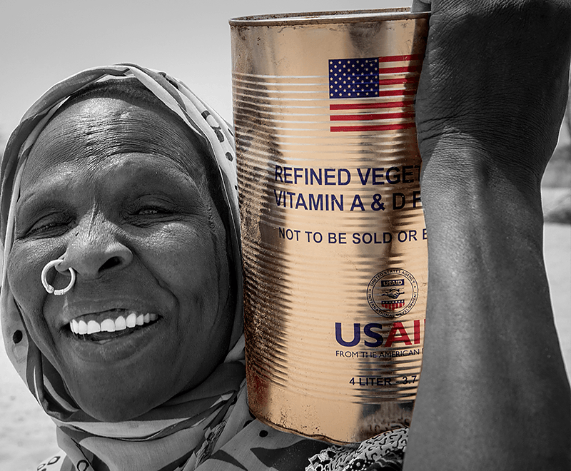 A woman carries a can of USAID-funded vegetable oil on her shoulder