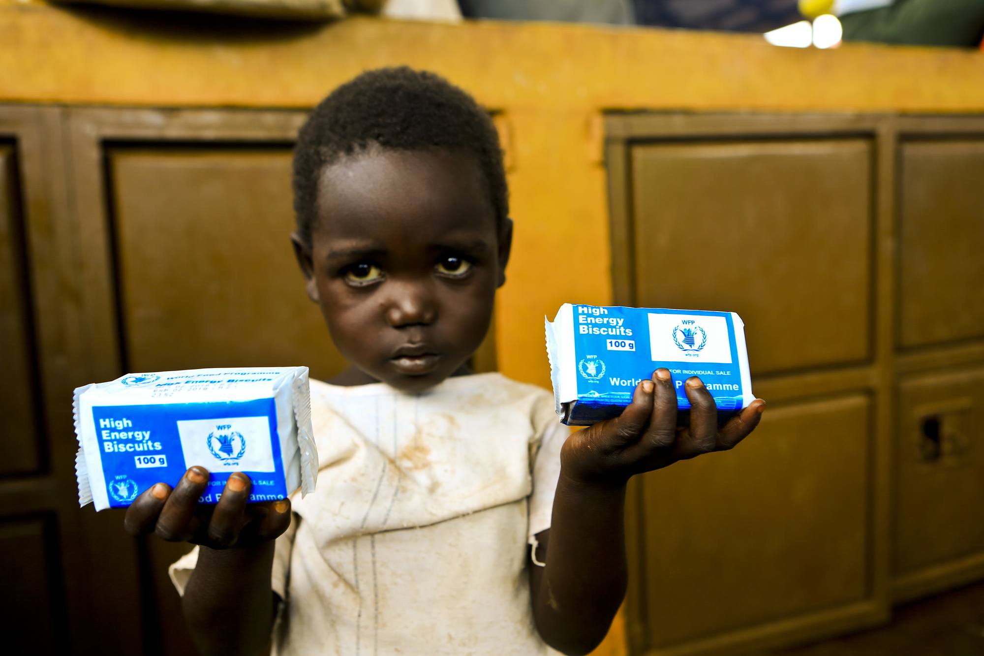 A small girl holds up two packets of High Energy Biscuits