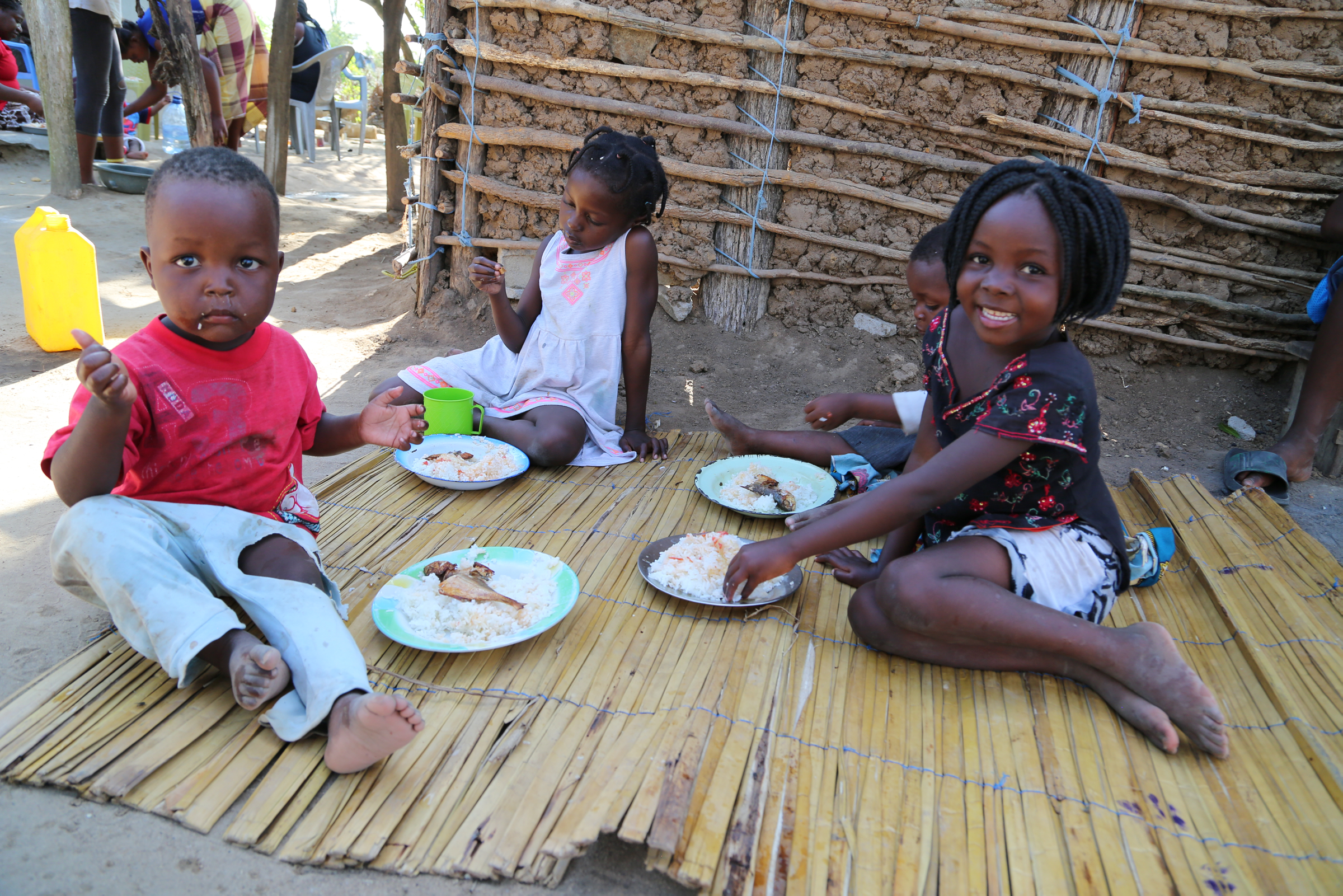 children eating on wooden mat and smiling