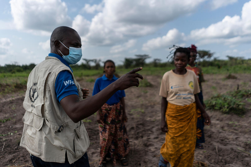 man in health mask speaks to group of farmers