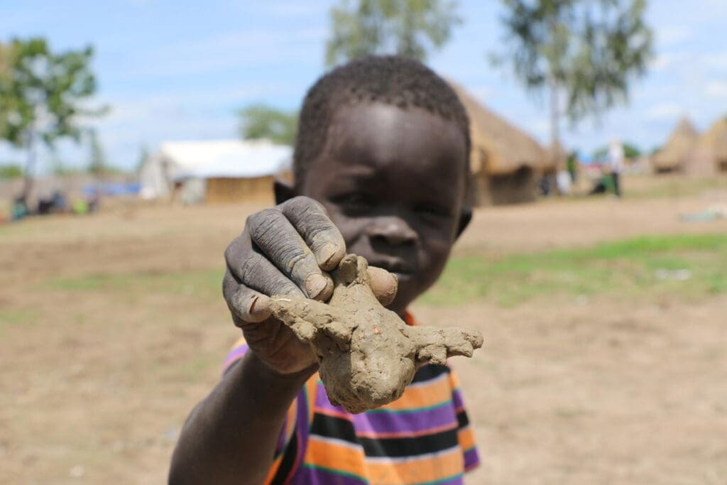 A young boy holds up a clay airplane.