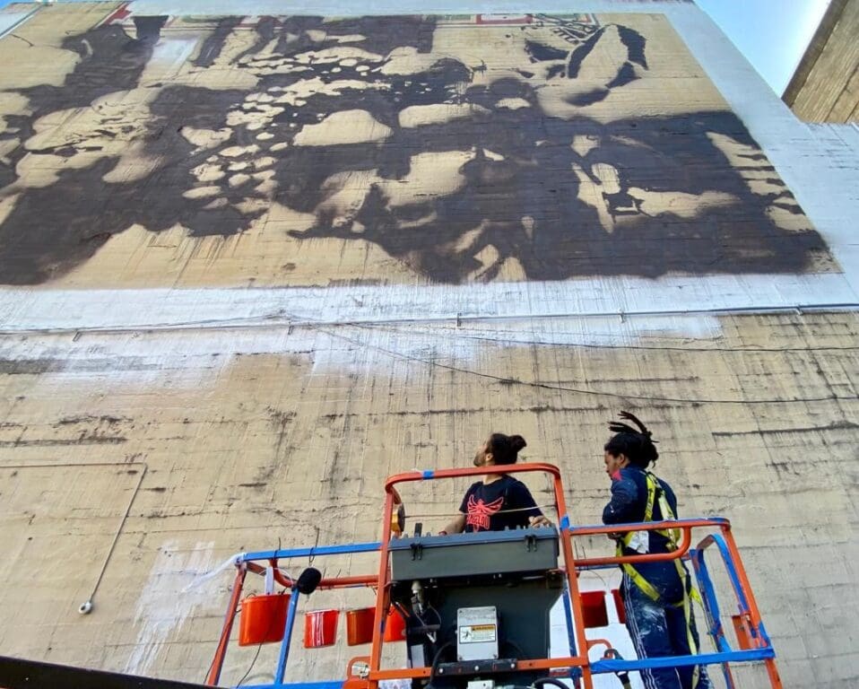 two artists painting the side of a building