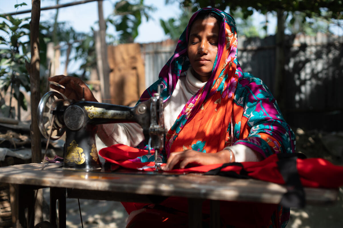 woman in red and pink headscarf using sewing machine