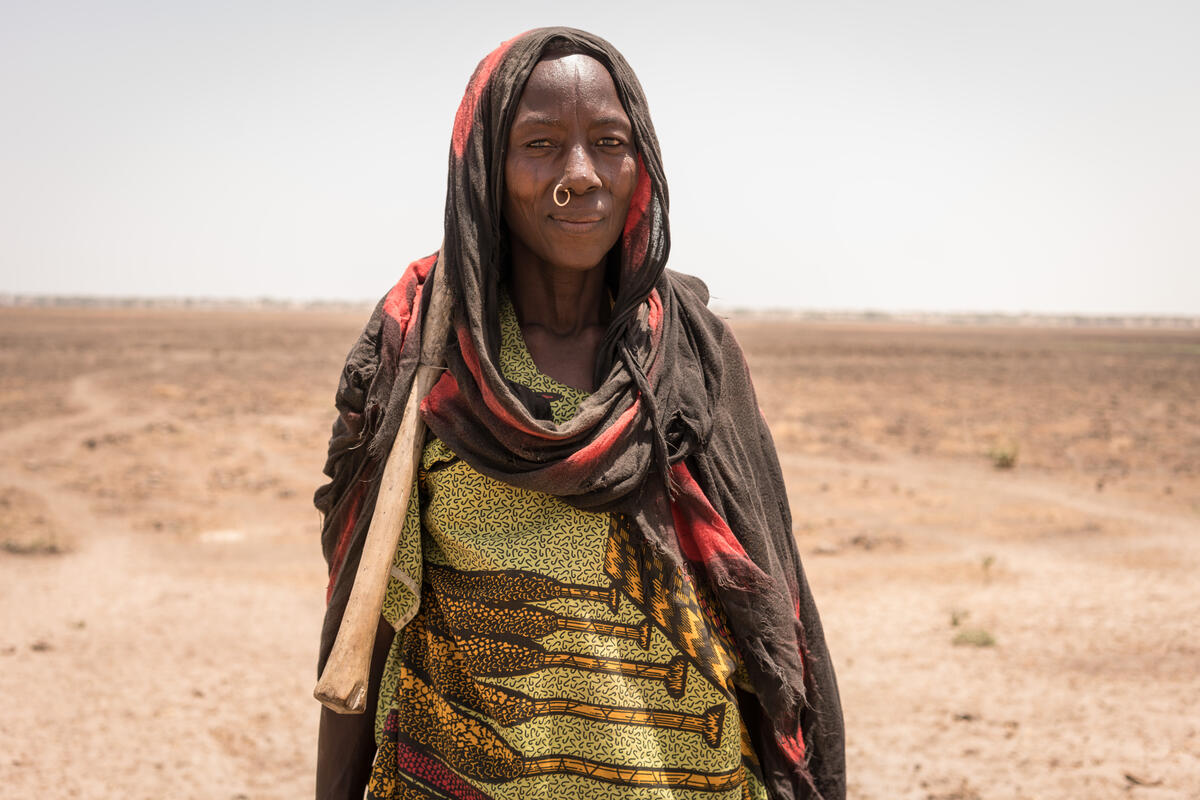 woman in brown and pink headscarf standing in desert field