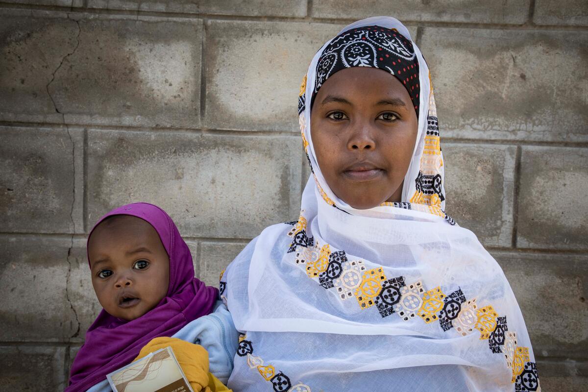 mother in white headscarf holding small child