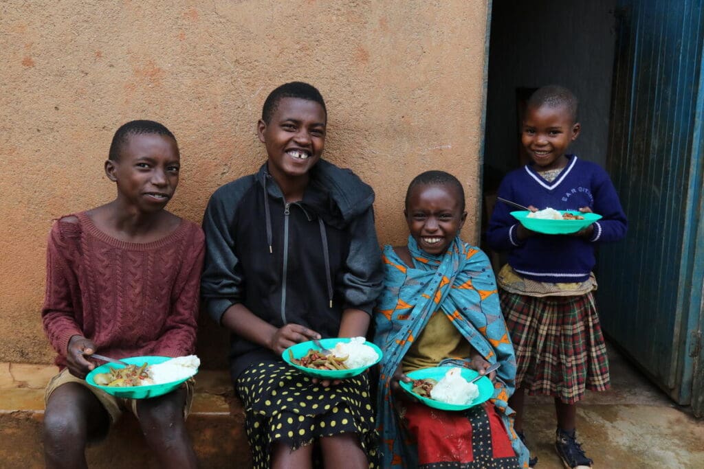 A family of four smiles, holding plates of food.
