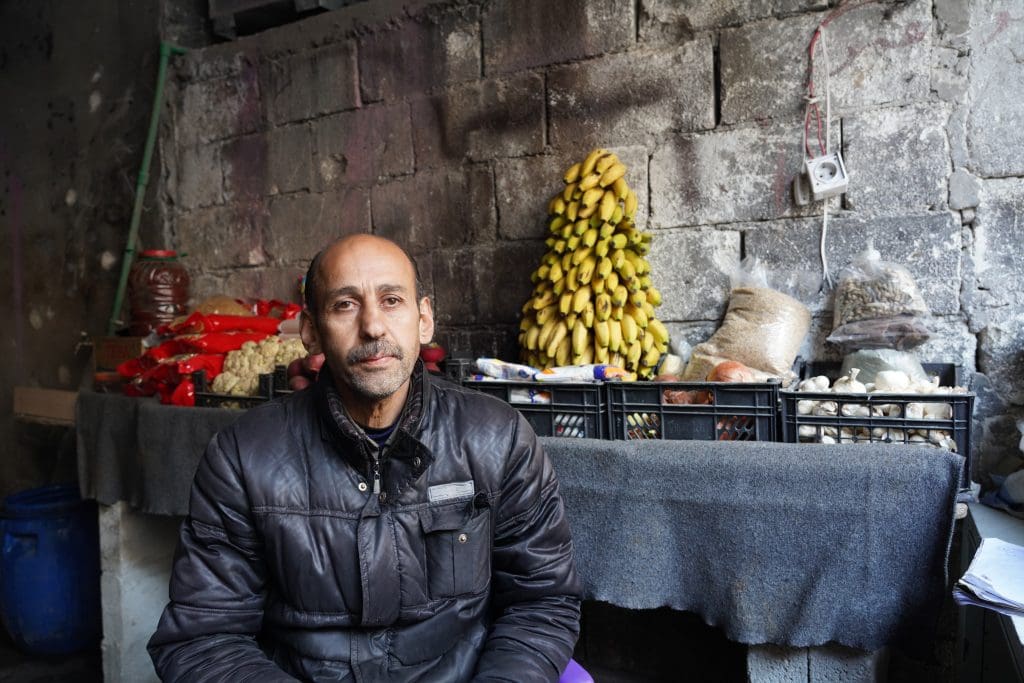 a man sits in front of his grocery store