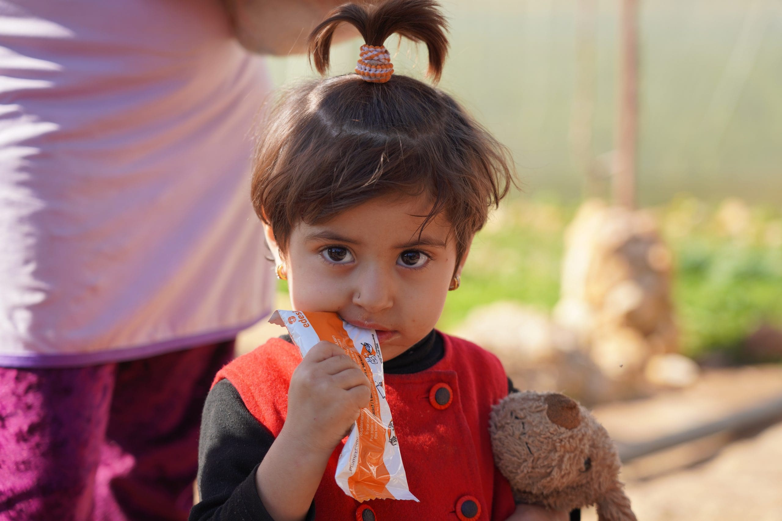 a young girl takes bite of nutrition bar