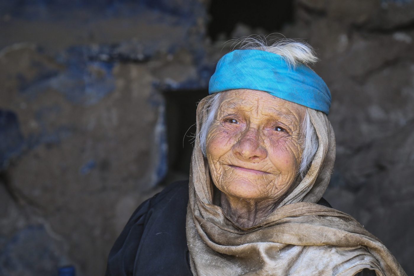 a woman in blue and grey headscarf smiles