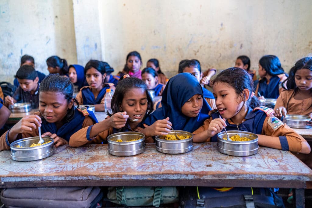 schoolgirls eating meals at table