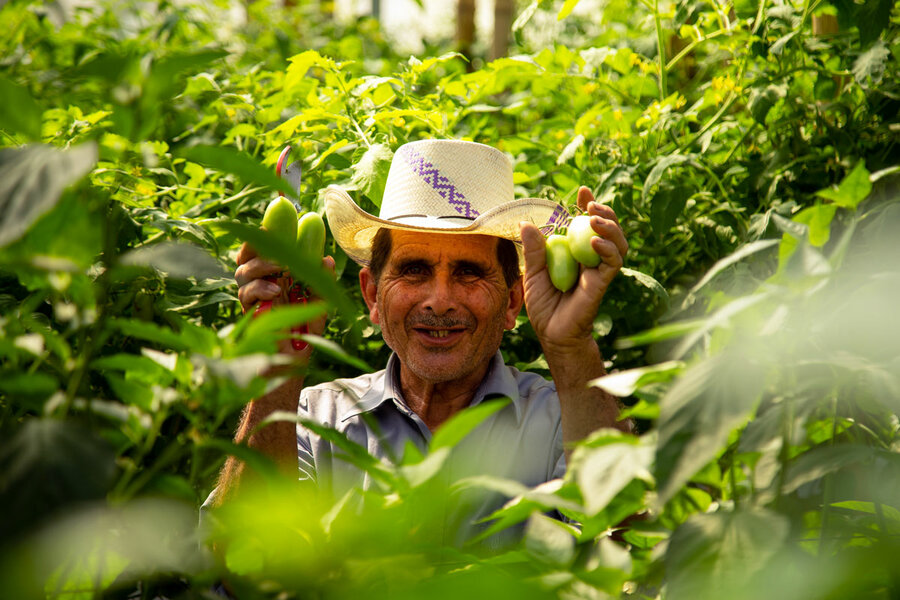 man smiles holding up green chilies