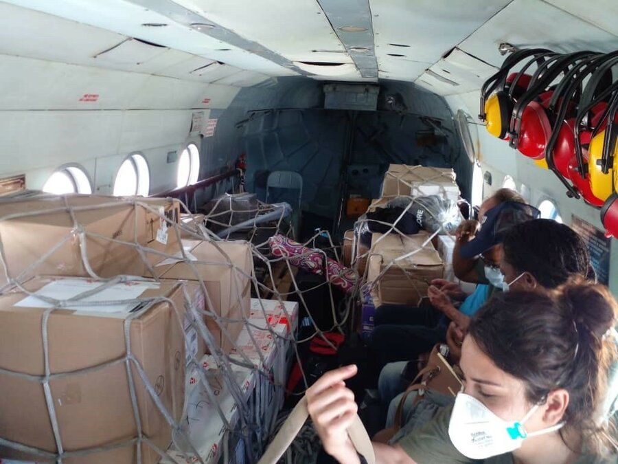 people in helicopter with boxes of supplies