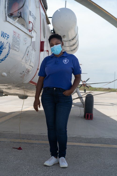 woman in blue shirt and COVID face mask in front of helicopter