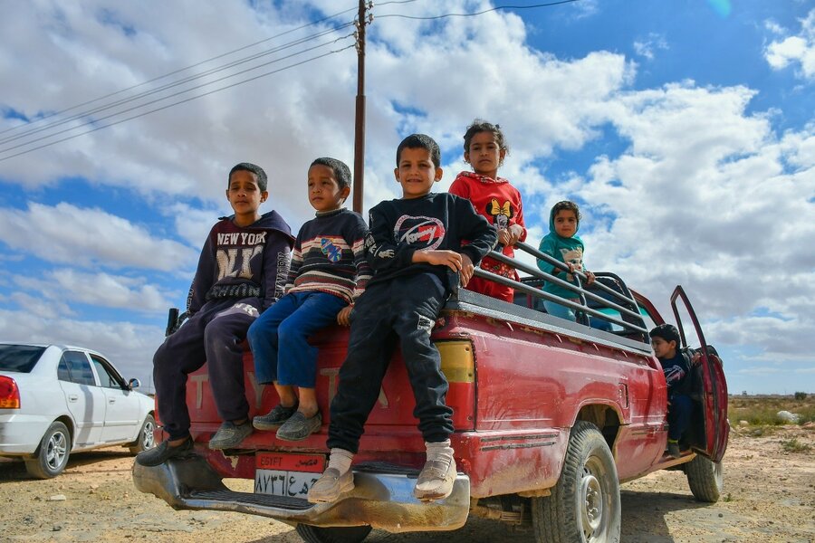 children sitting in the back of a red truck