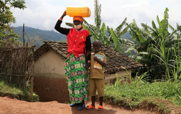 mother carrying water on her head walks with son