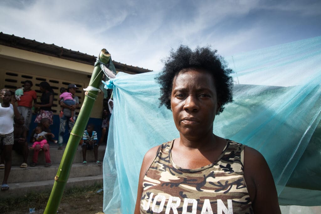 woman in camo tank top stands in front of tent