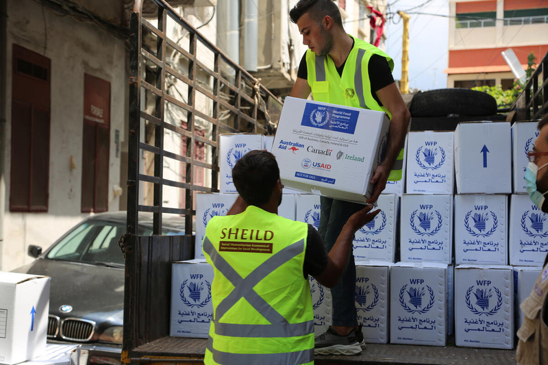 two WFP workers lift boxes of food into truck