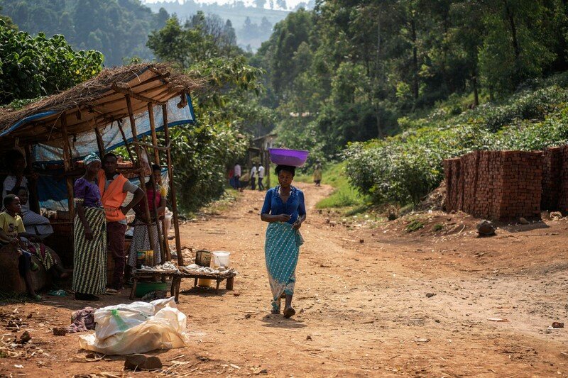 woman carrying basket on her head down dirt road