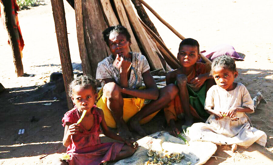 mother and children sitting on ground eating