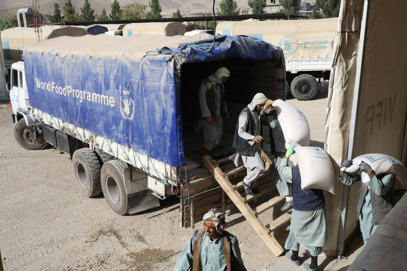 men offloading bags of food from truck