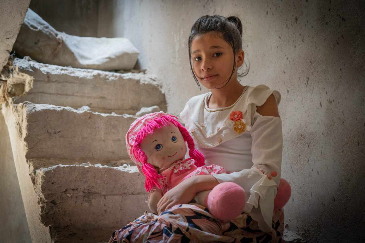 young girl holding stuffed doll on staircase