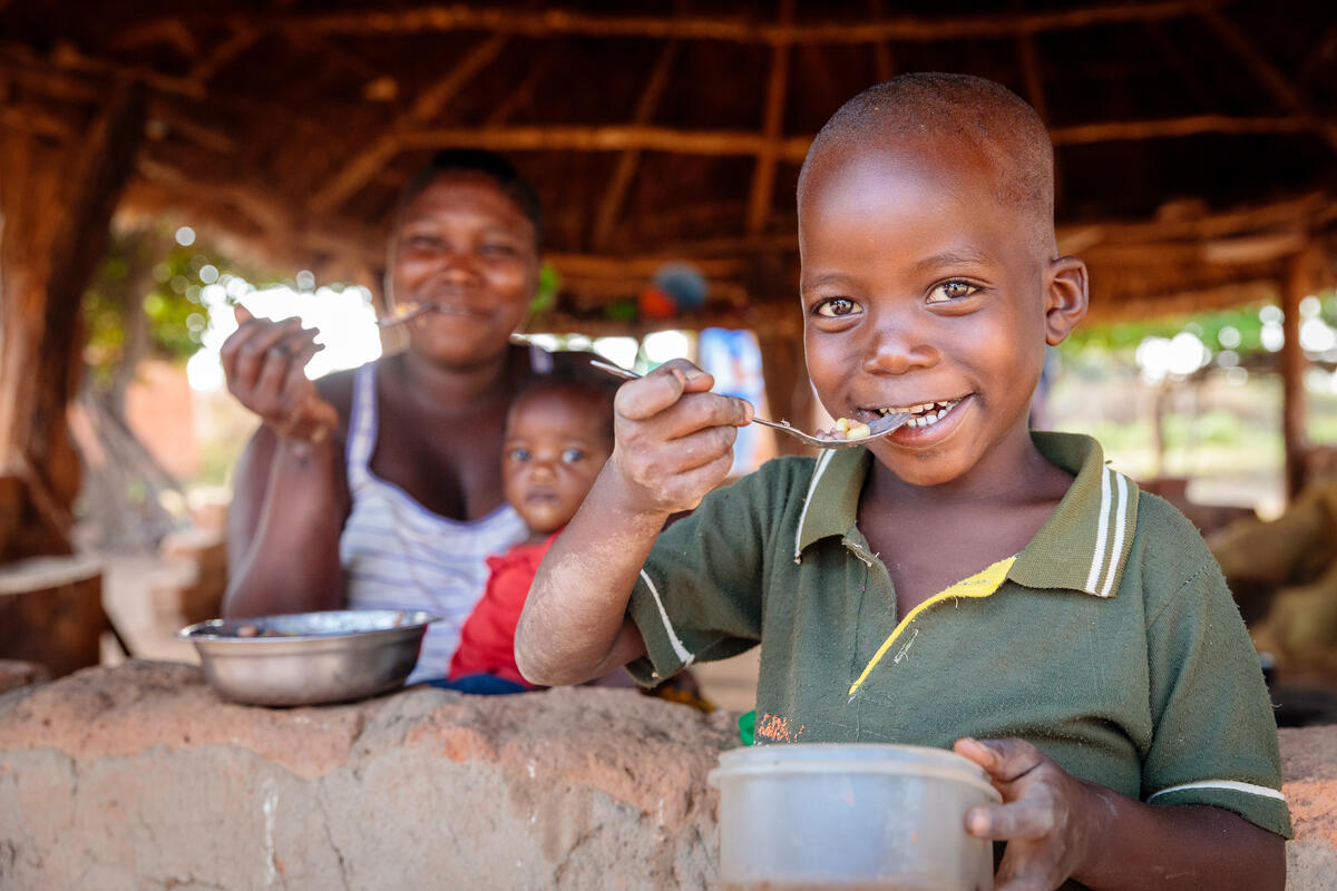 boy smiling while eating meal with family