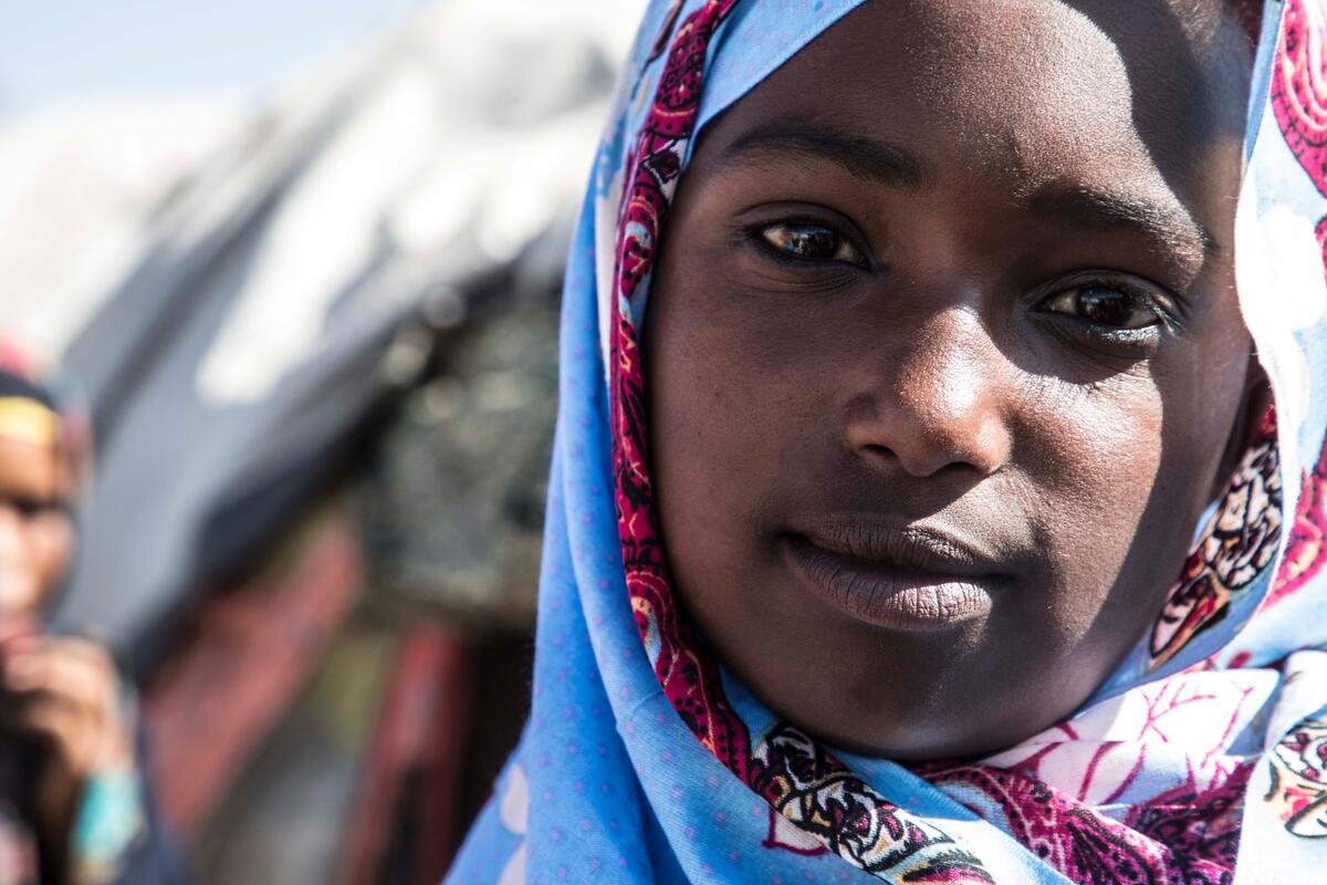 girl in purple headscarf looks at camera