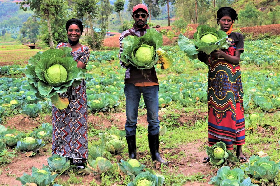 farmers holding up vegetables in garden