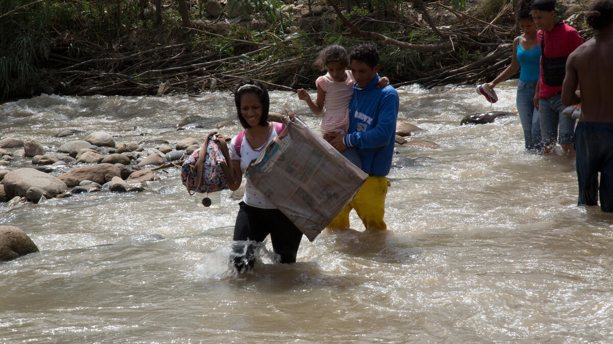 family holding their belongings and crossing river