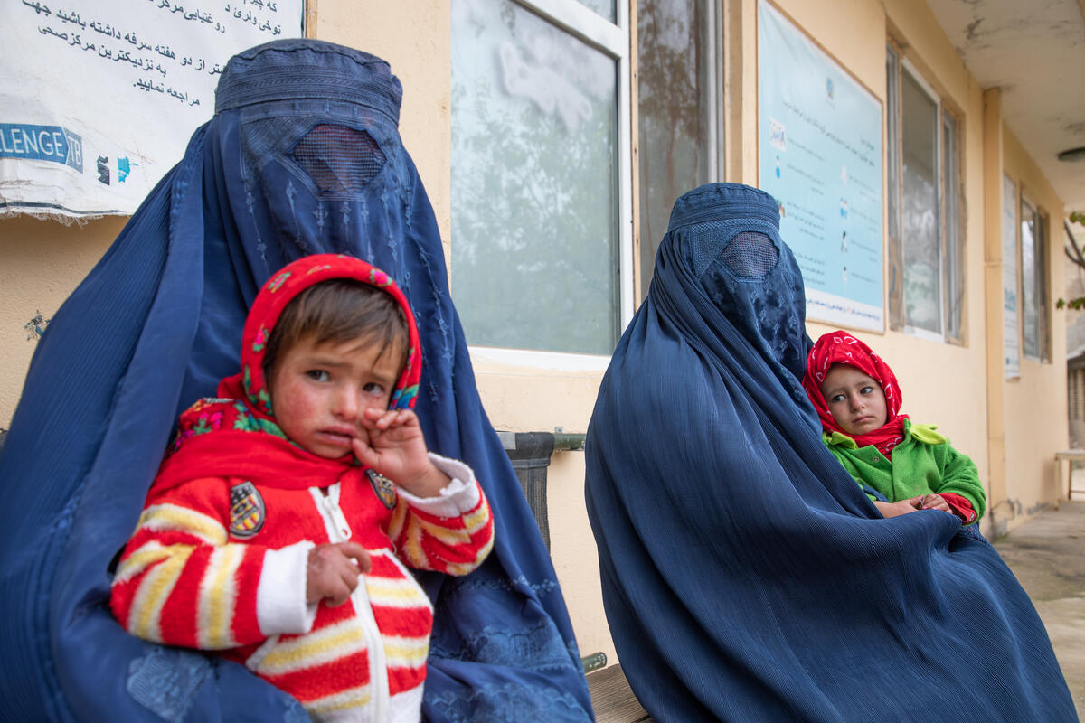mothers wearing blue burqas and holding their children at nutrition center