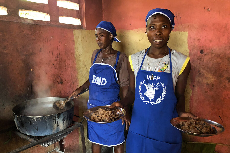 women in blue WFP aprons cooking over hot stove