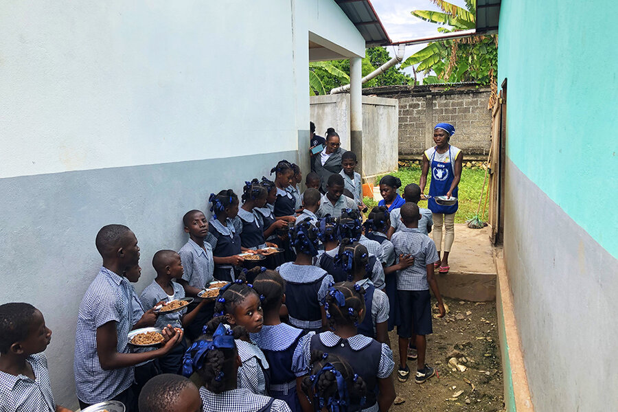 students in blue uniforms line up for a meal