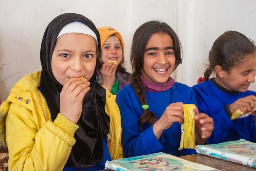 schoolgirls in yellow and blue outfits eating lunch