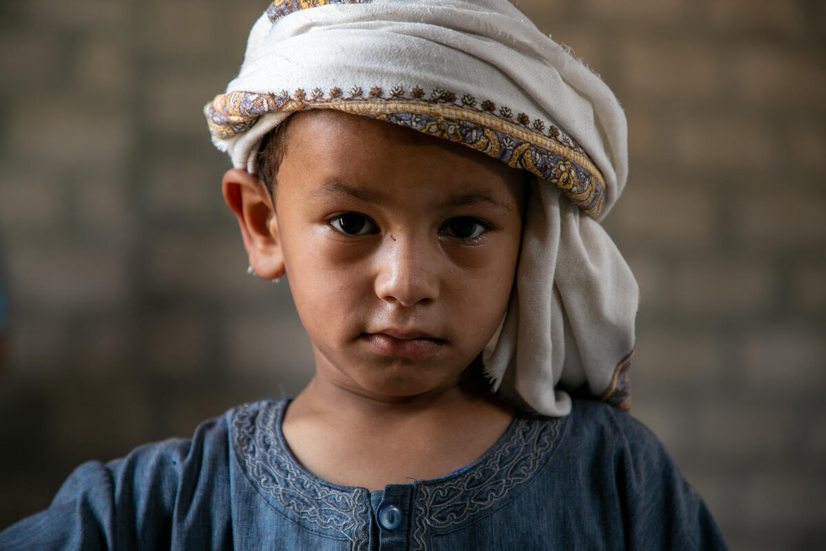 young boy in white headscarf and blue shirt