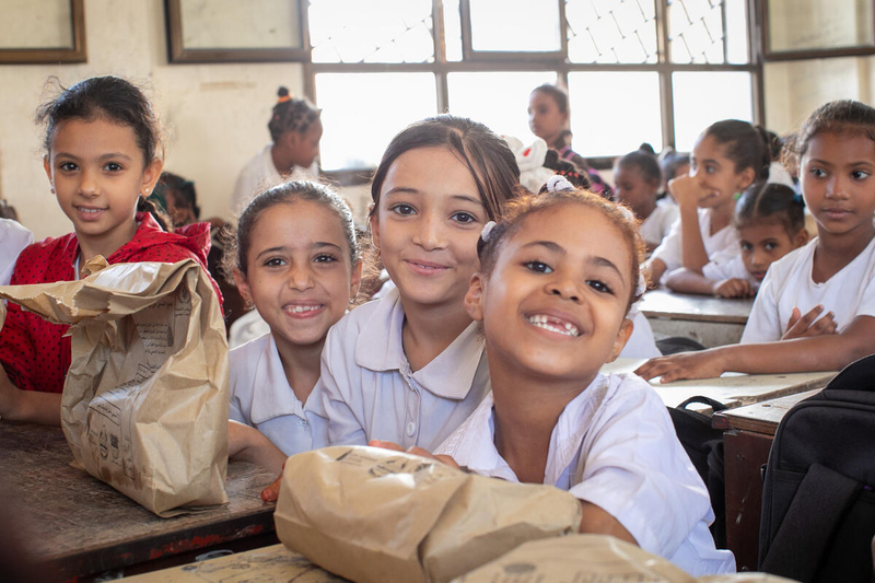 schoolgirls in white shirts smiling and eating lunch