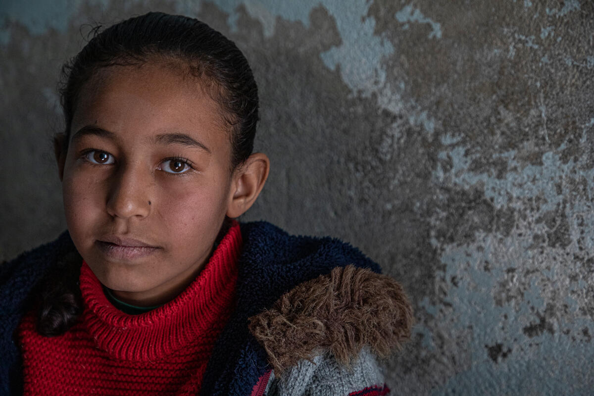 girl in winter coat smiles softly at camera