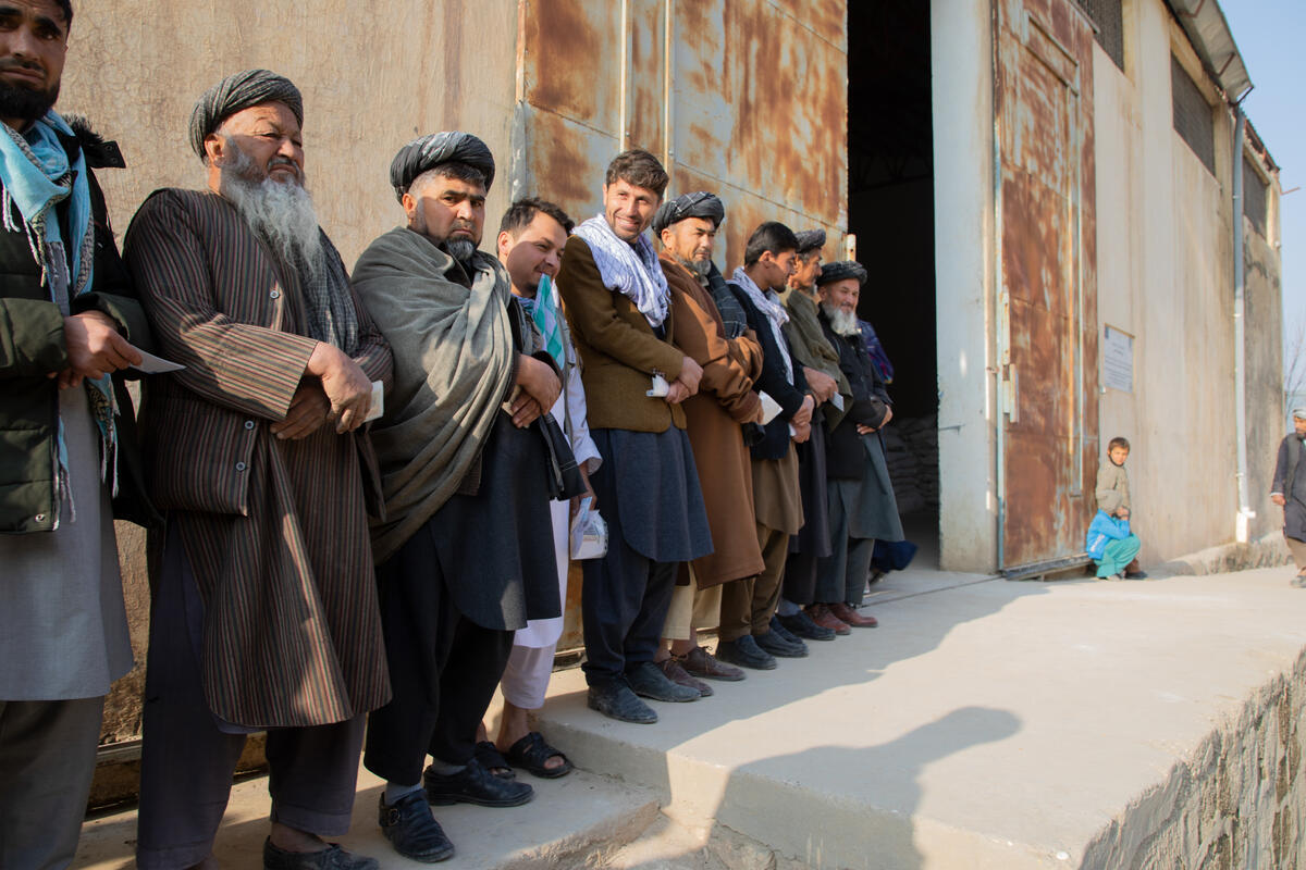 men waiting in line outside building for food