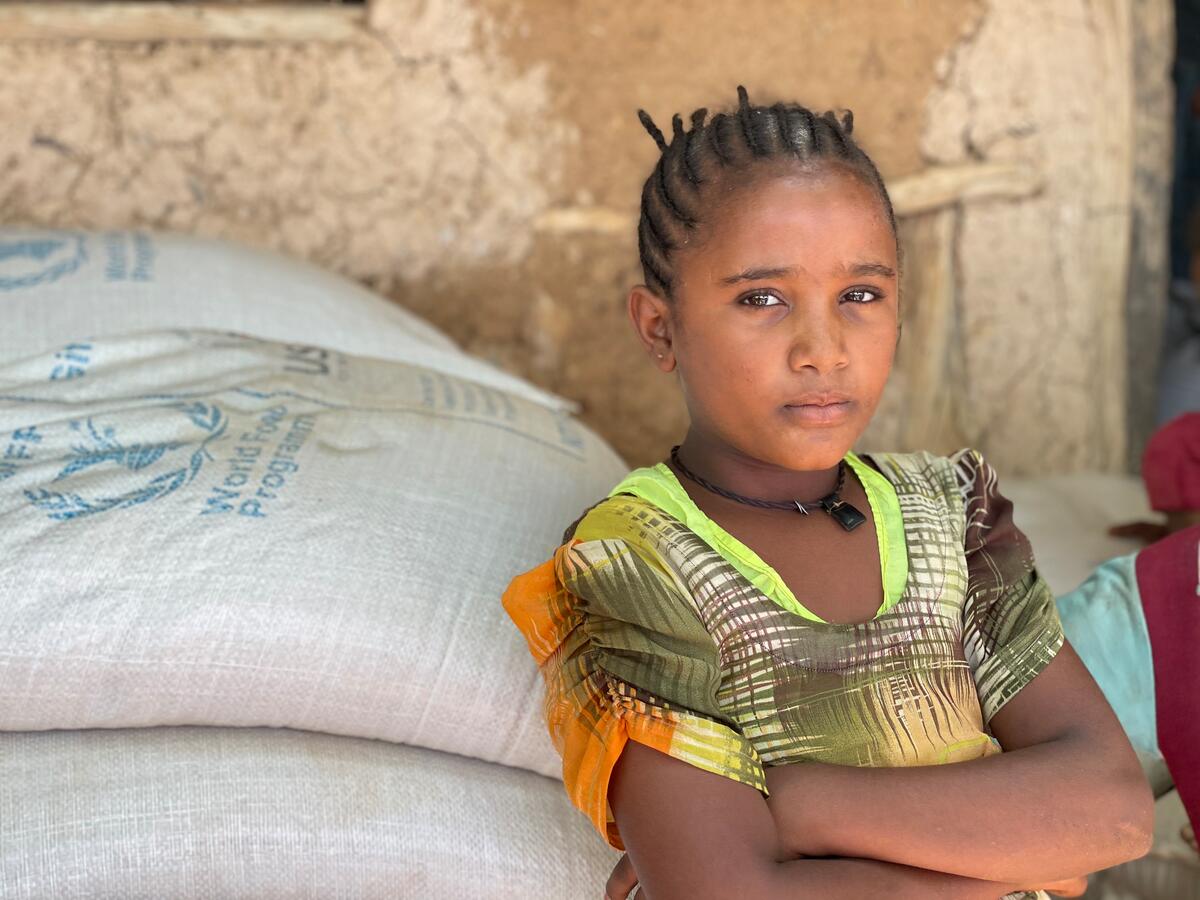 young girl in green shirt standing next to bags of food