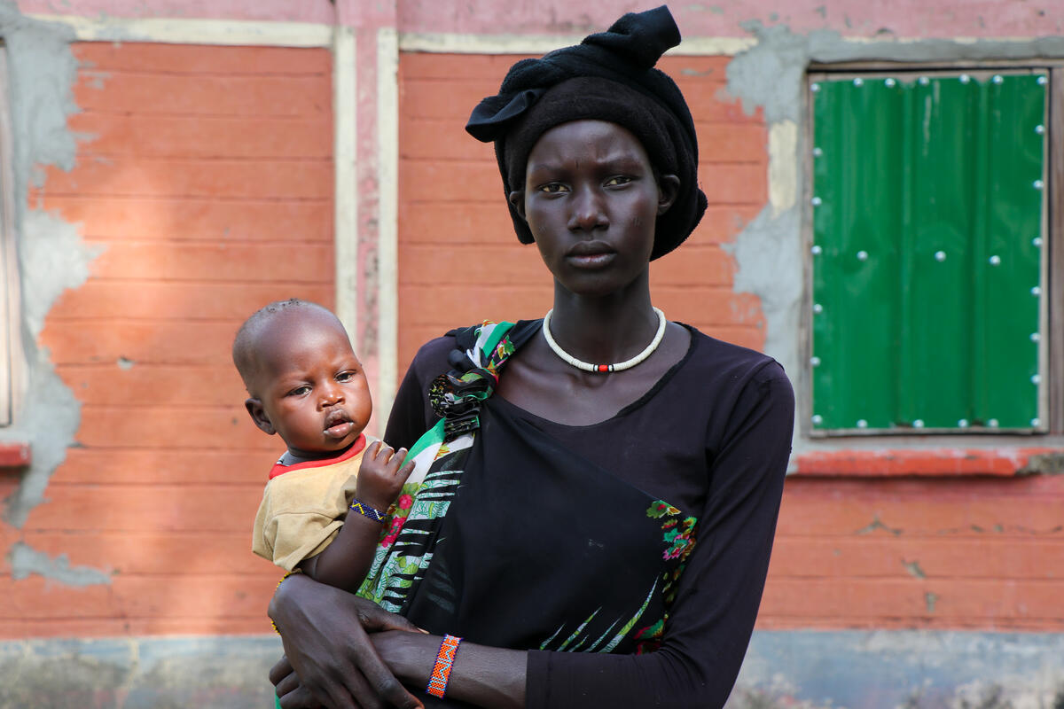 mother in black head wrap holding baby