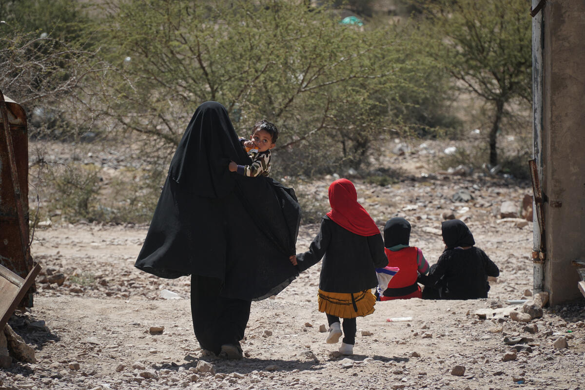 woman in black burqa walking with small children