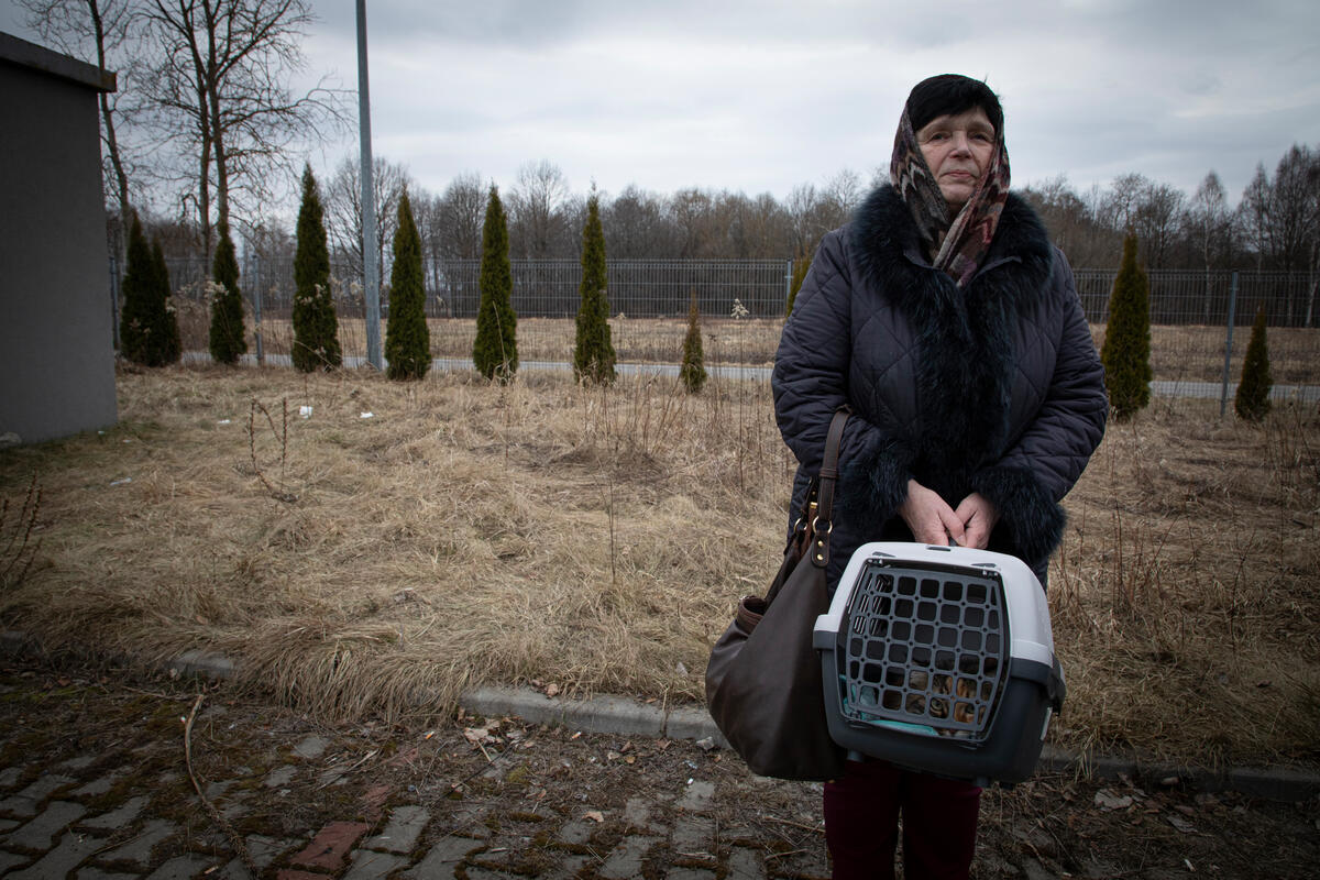 woman in winter clothes holding cat in crate