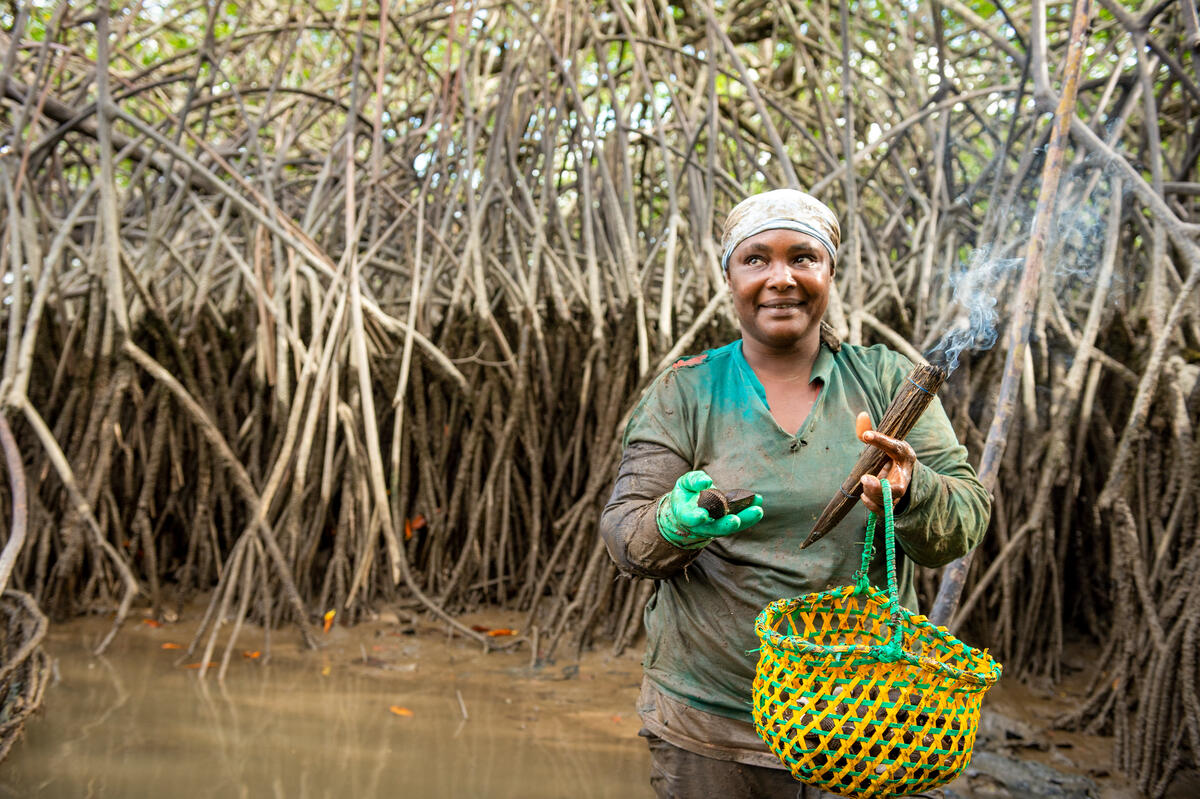 woman holding basket of oysters knee-deep in water