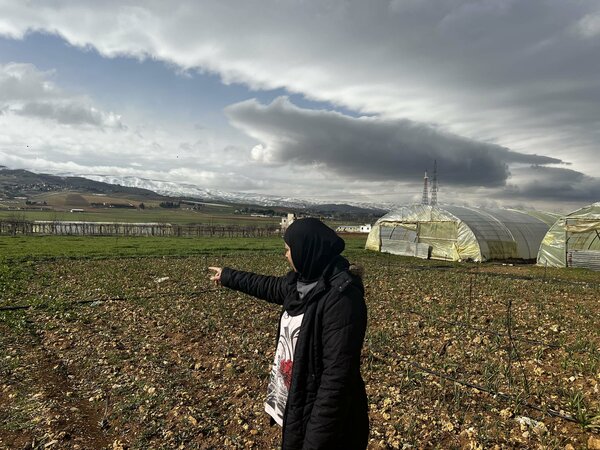 woman gesturing at field of crops