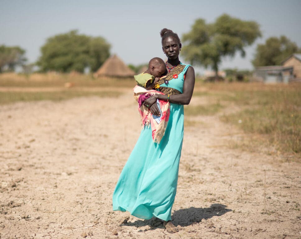 South Sudan. Mary and her baby Ahok walk to the nutrition centre.