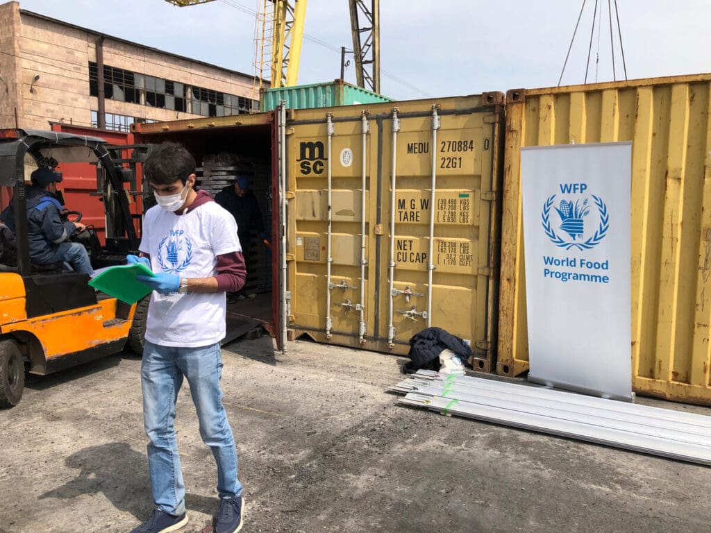 A WFP worker stands in front of shipping containers.