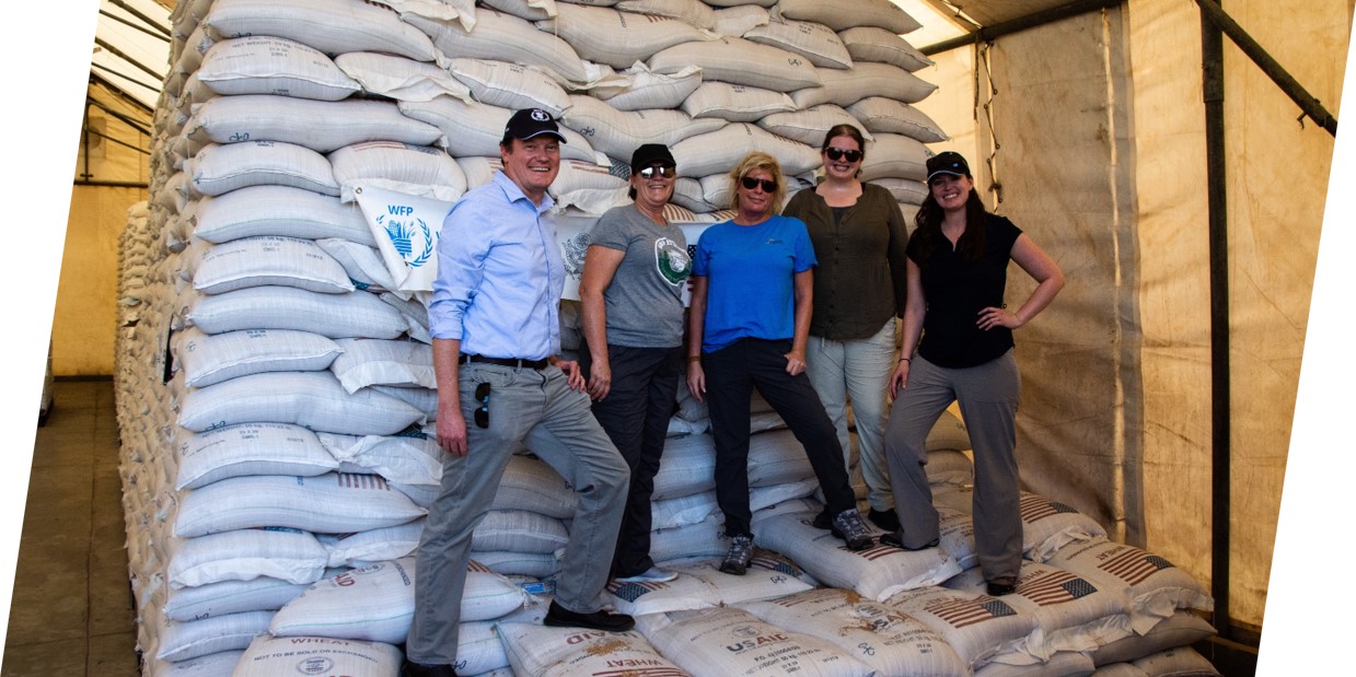 Farmers stand in front of bags of food