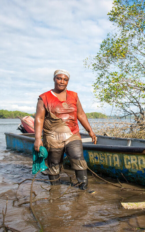 woman standing in muddy boots in front of boat