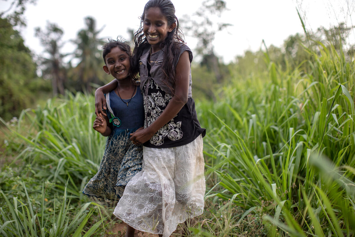 Sisters run through field in Sri Lanka