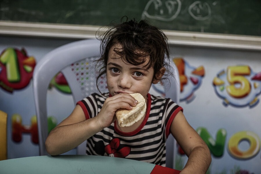 A young girl eats bread distributed by WFP, at a school shelter in Gaza.